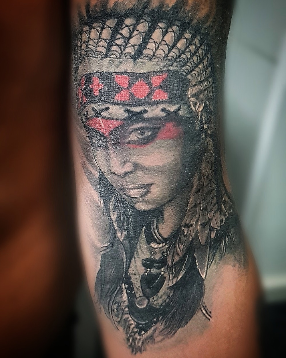 Realistic portrait tattoo of a woman in a headdress with red war paint